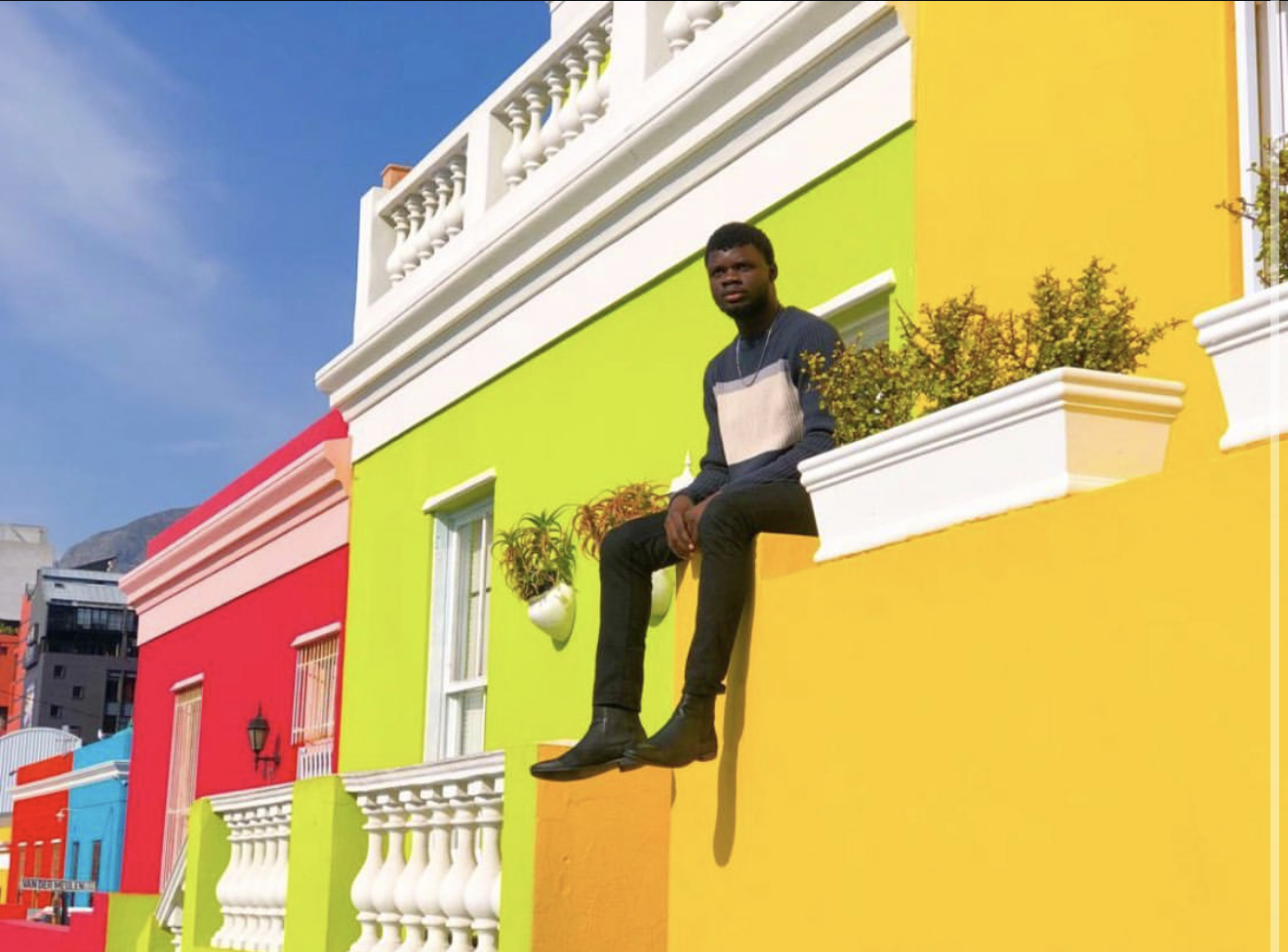 The founder of amafirka seated on a bright wall in the Bo-Kaap